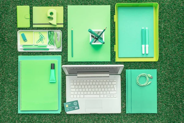 Material de escritório verde e laptop na grama — Fotografia de Stock