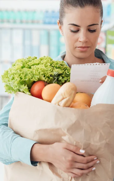 Femme vérifiant la liste d'épicerie au supermarché — Photo