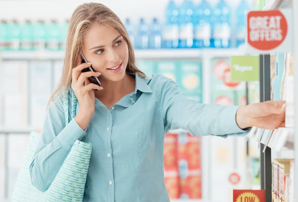 Vrouw met telefoontje in supermarkt — Stockfoto