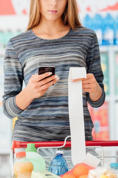 Frau kontrolliert Lebensmittelquittung im Supermarkt — Stockfoto