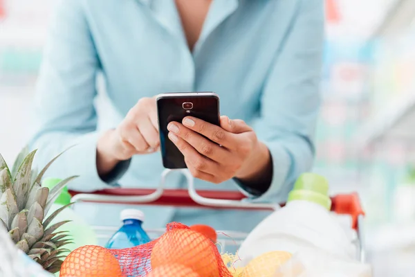 Vrouw verbinden met telefoon bij supermarkt — Stockfoto