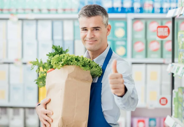 Supermarket úředník drží pytel s potravinami — Stock fotografie