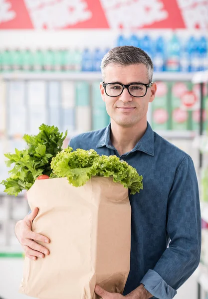 Hombre llevando bolsa de comestibles en el supermercado —  Fotos de Stock