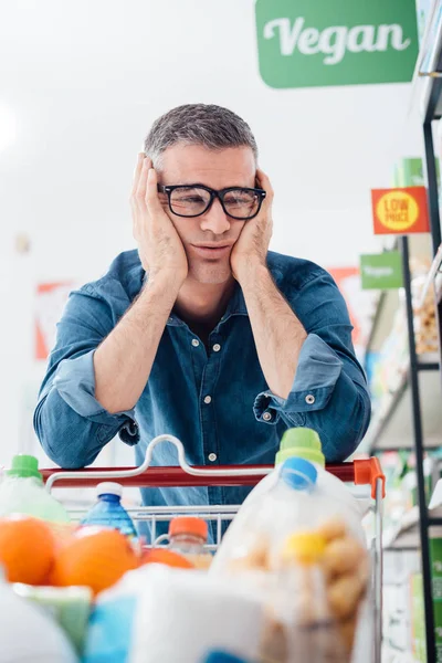 Грустный человек, покупающий в супермаркете — стоковое фото