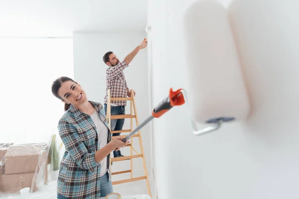 Couple painting house using rollers — Stock Photo, Image