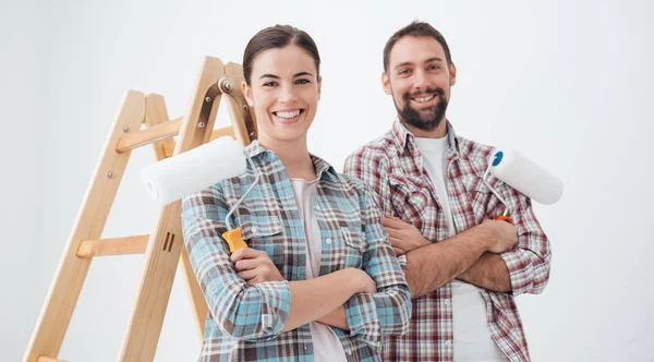 Couple souriant et tenant rouleaux de peinture — Photo