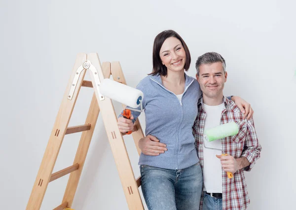 Couple heureux posant avec des rouleaux de peinture — Photo