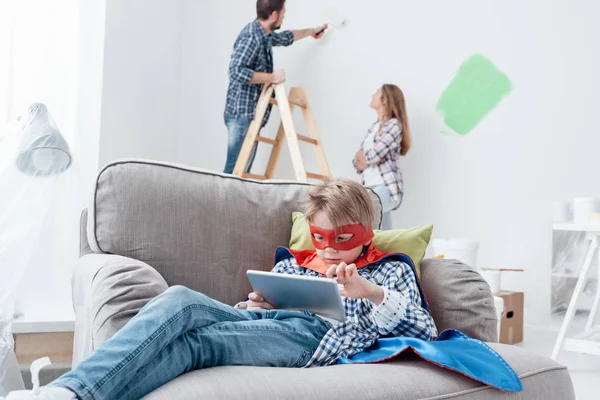Superhrdina chlapec hraje s tabletem v křesle — Stock fotografie