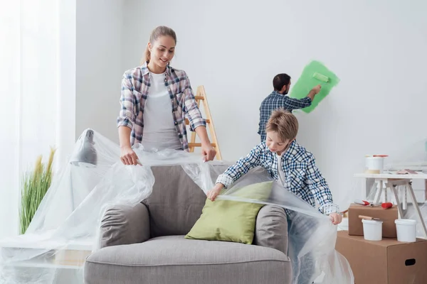 Junge mit Mutter deckt Möbel mit Laken ab — Stockfoto