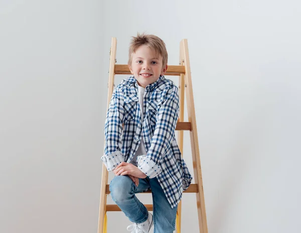 Cute boy sitting on wooden ladder — Stock Photo, Image