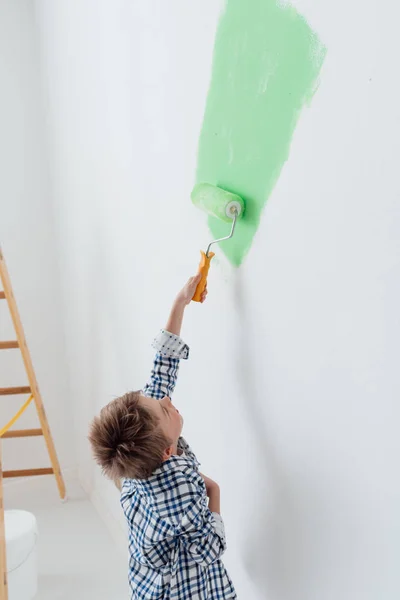 Симпатичный мальчик рисует стены дома — стоковое фото