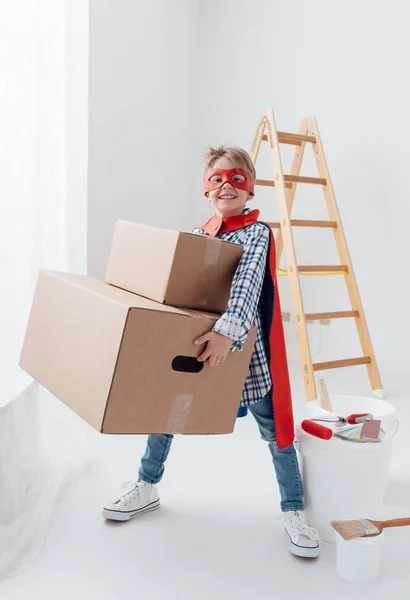 Menino super-herói carregando caixas pesadas — Fotografia de Stock