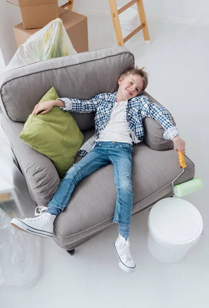 Niño acostado en sillón con rodillo de pintura —  Fotos de Stock