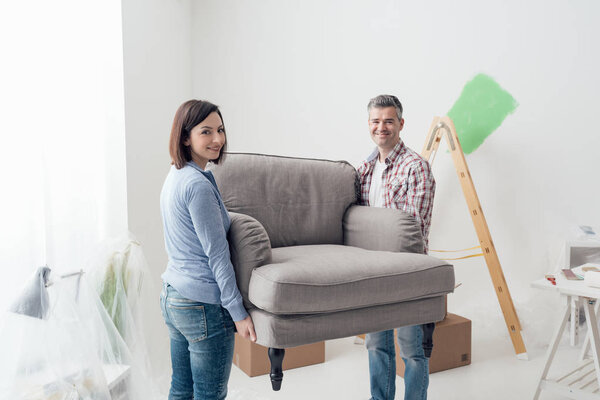 Couple carrying armchair in new house