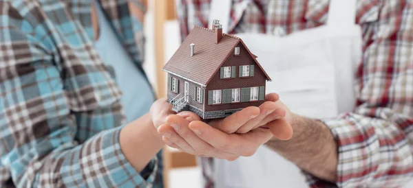 Hombre y mujer sosteniendo casa modelo — Foto de Stock