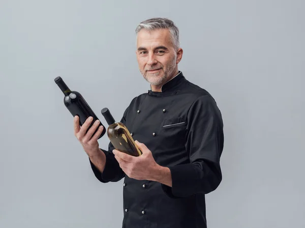 Professional chef comparing wine bottles — Stock Photo, Image