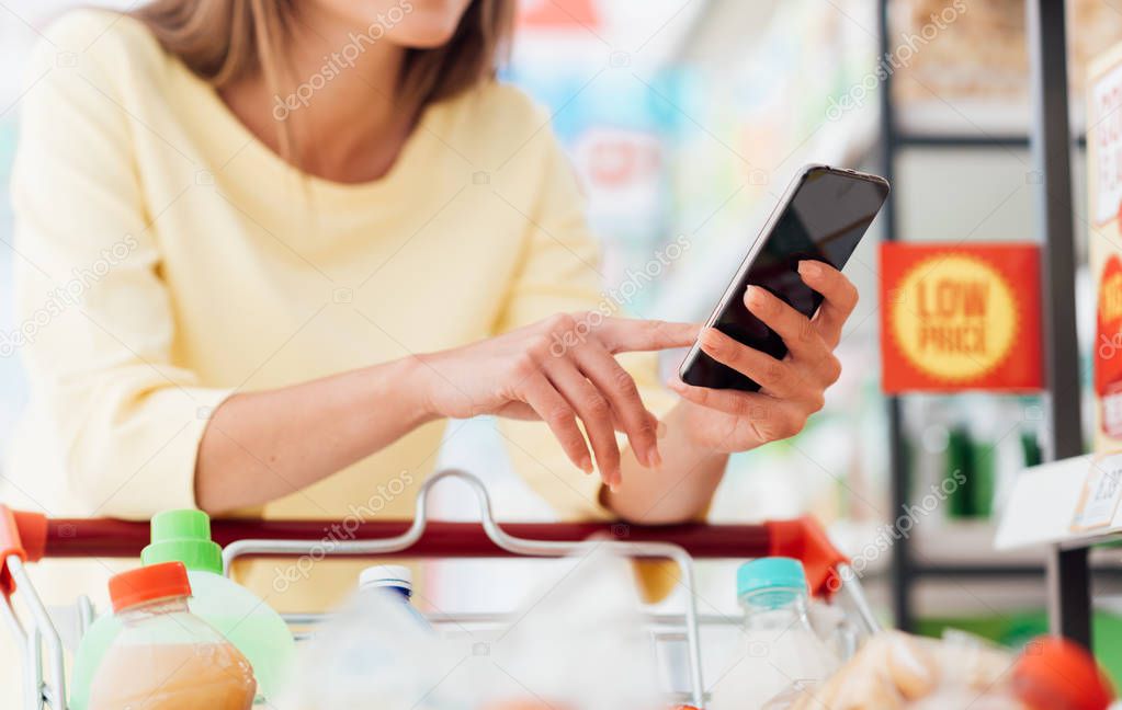 Woman using smart phone at supermarket 