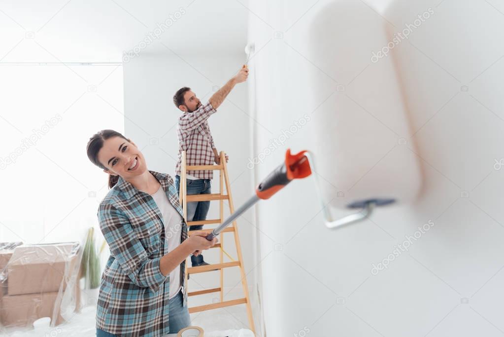 couple painting house using rollers
