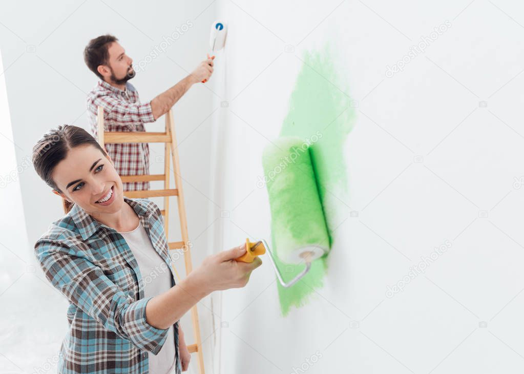 Happy couple painting walls in house