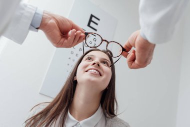 ophthalmologist putting glasses on woman   clipart