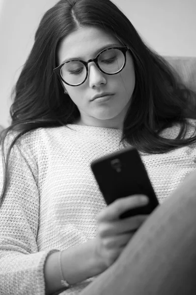 Mädchen liegt auf Sofa und textet mit Smartphone — Stockfoto
