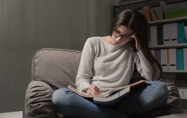 Flickan sitter i fåtölj med bok — Stockfoto