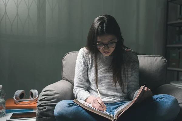 Flickan sitter i fåtölj med bok — Stockfoto