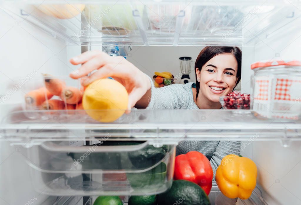 Woman taking lemon out of fridge