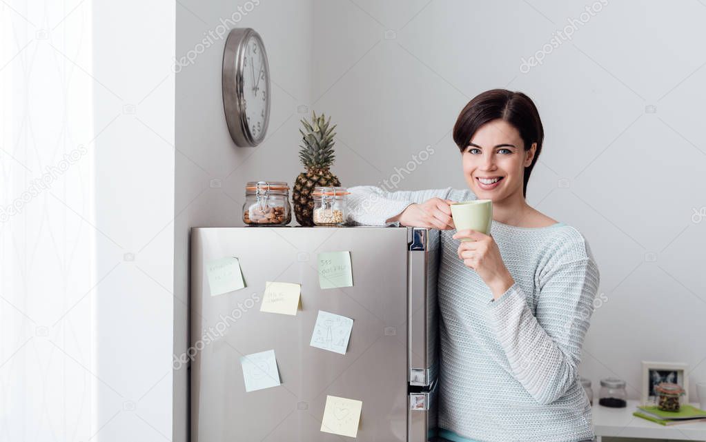 Young woman leaning on fridge