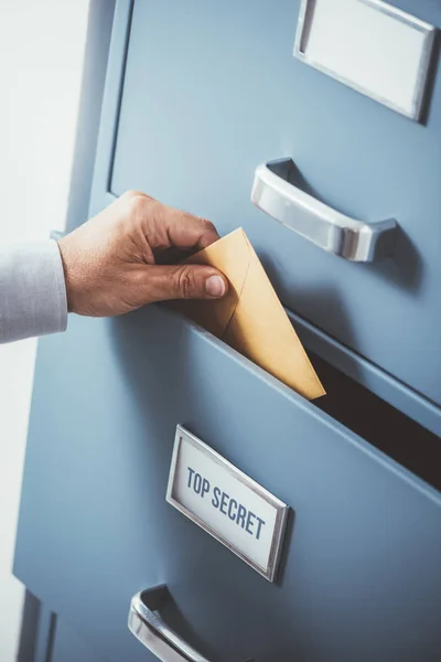 Businessman putting envelope into drawer — Stock Photo, Image