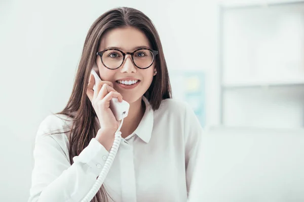 Lachende secretaris beantwoorden van telefoongesprekken — Stockfoto