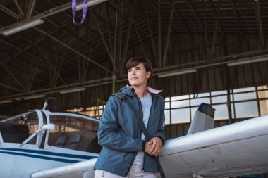 uçak kanadı üzerinde yaslanmış kadın pilotu