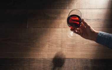 Elinde kırmızı şarap kadehi tutan adam.
