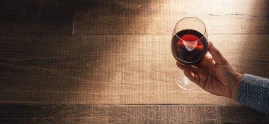 Elinde kırmızı şarap kadehi tutan adam.