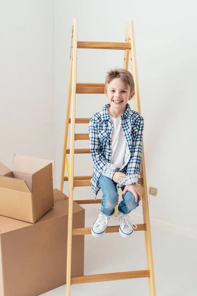 Young boy sitting on ladder — Stock Photo, Image