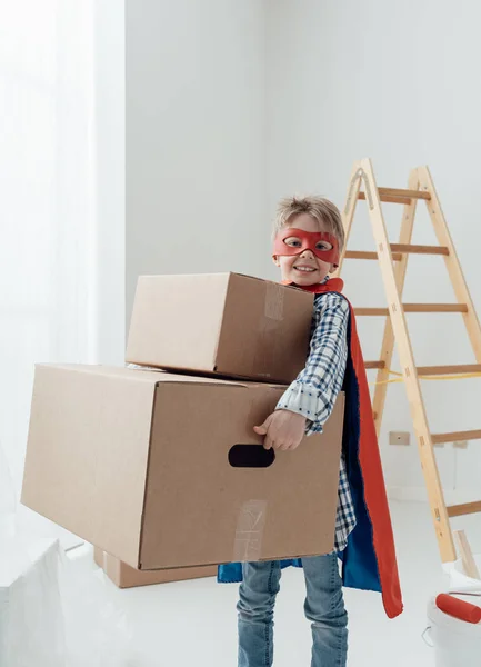 Menino super-herói carregando caixas pesadas — Fotografia de Stock