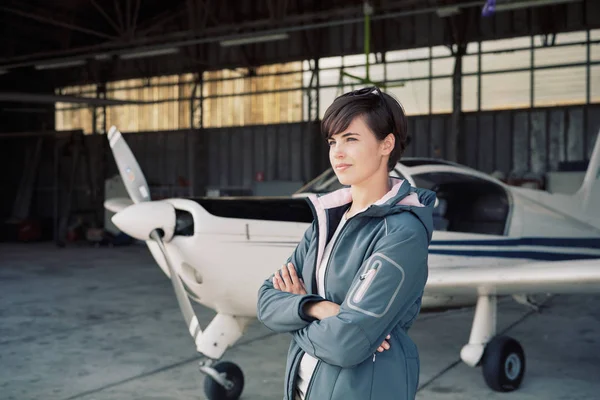 Piloto femenina posando en el hangar —  Fotos de Stock