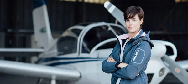 Vrouwelijke piloot poseren met vliegtuig — Stockfoto