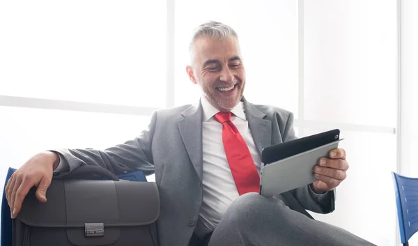 Businessman in waiting room with tablet