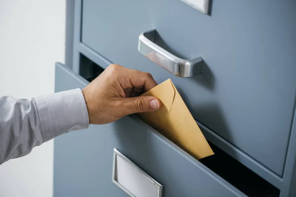 Empresário colocando um envelope na gaveta — Fotografia de Stock