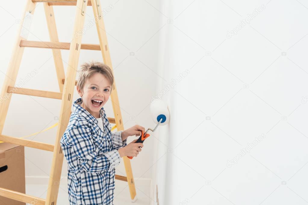 Happy cute boy painting wall