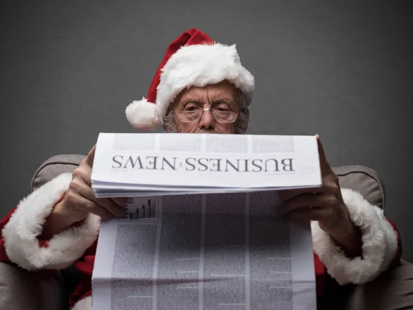 Santa Claus läsa ekonominyheter — Stockfoto