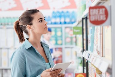 Kadının bakkal mağazada alışveriş ve dijital dokunmatik ekran tablet, teknoloji ve ticaret kavramı kullanarak yapması