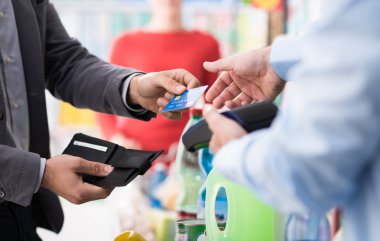 Süpermarkette alışveriş ve mağaza çıkış olarak bir kredi kartı ile ödeme bakkal yapıyor erkek