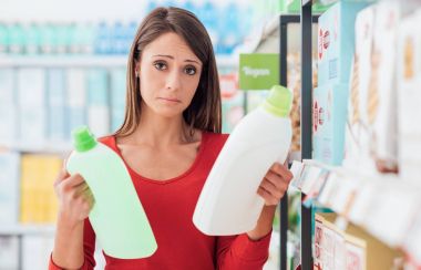 Woman shopping at the supermarket and comparing detergent products, she can't decide which one is the best clipart