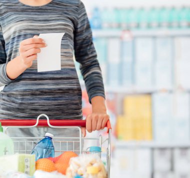 Genç kadın süpermarket, alışveriş o bir kart bastırmak ve okuma bir bakkal listesi