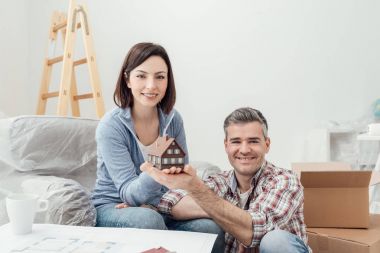 Mutlu çift bir modeli ev tutan gülümseyerek, onların ev birlikte, Emlak ve inşaat kavramı yapıyorlar