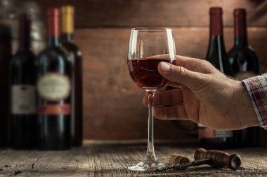 Şarap tadımı rustik kiler ve şarap barı deneyimi: bir bardak kırmızı şarap lezzetli ve mükemmel şarap şişeleri toplama arka planda tutan sommelier