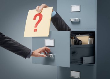 İşadamı içinde bir soru işareti içeren bir dosyayı bir büro memuru veren bir dosya dolabı: risk, belirsizlik yönetimi ve kavramı meydan