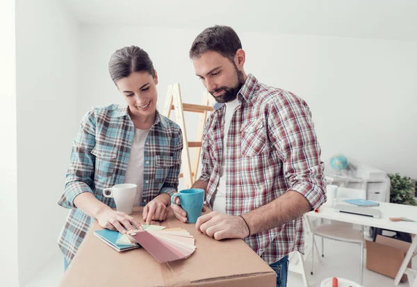 Onların yeni evime taşınmaya ve ev bir makyaj yapıyor genç çift gülümsüyor, onlar renk örneklerini toplama vardır